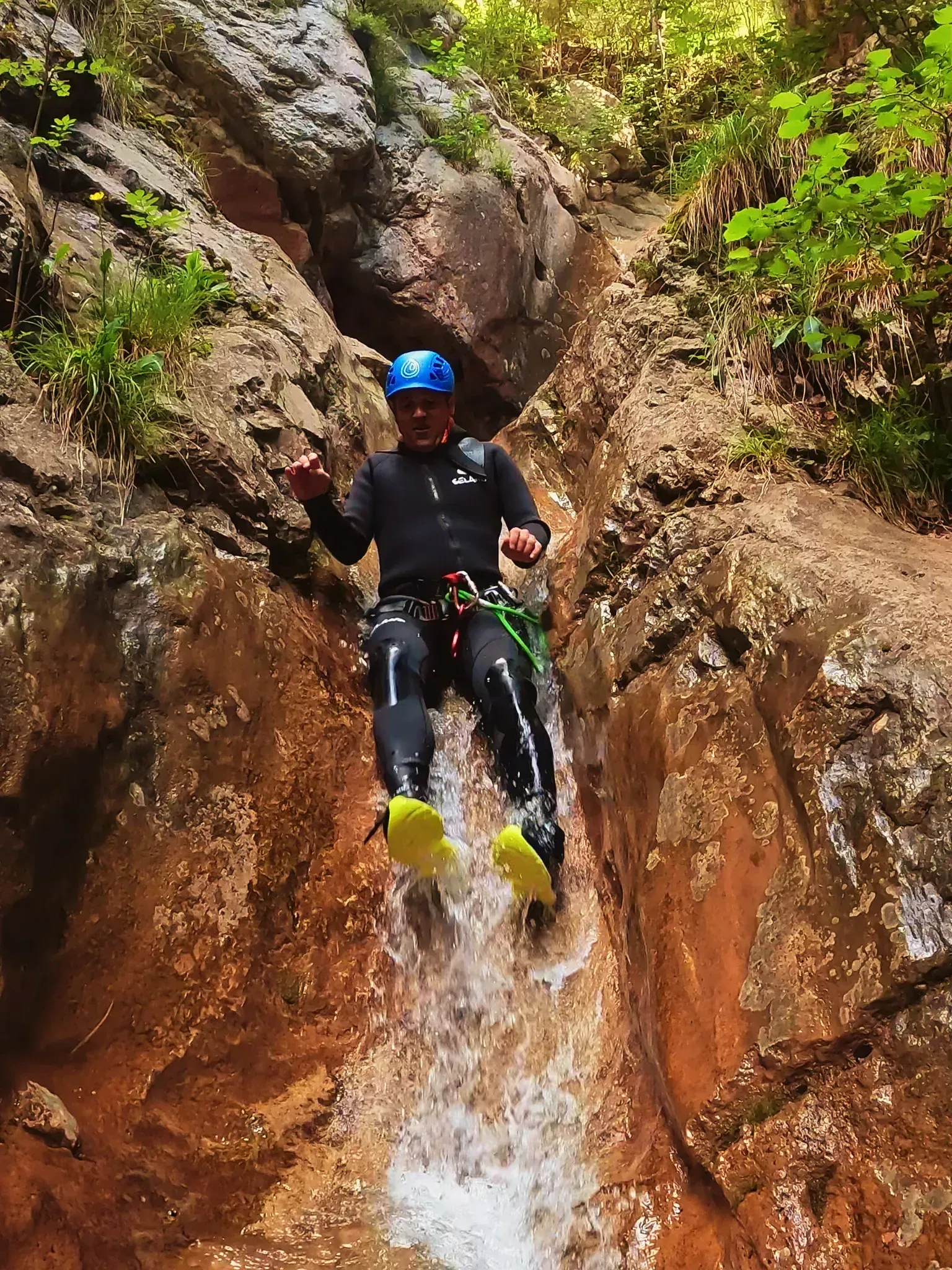 Un hombre se desliza por una cascada en un cañón.