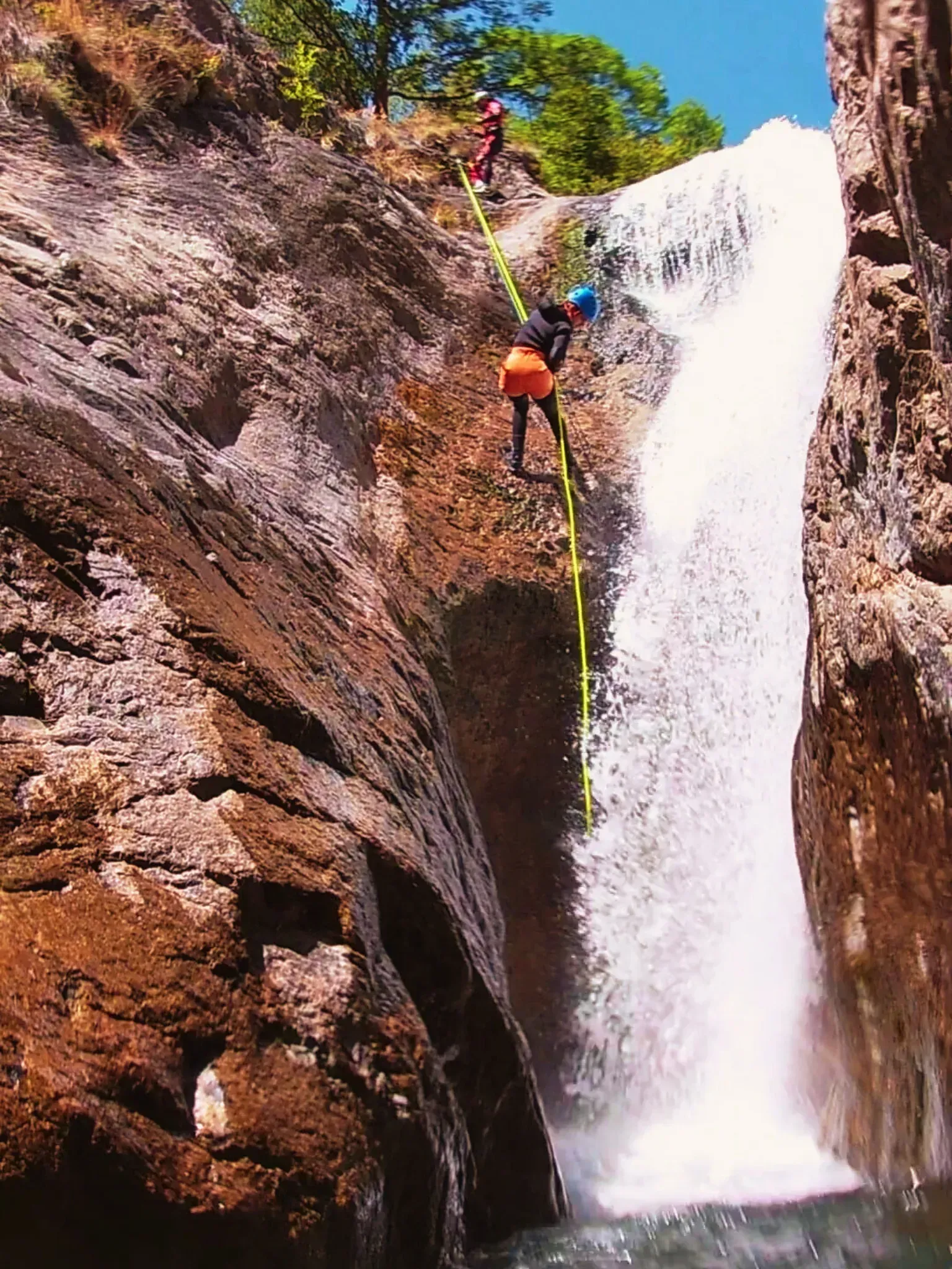 Una persona está escalando una cascada con una cuerda.