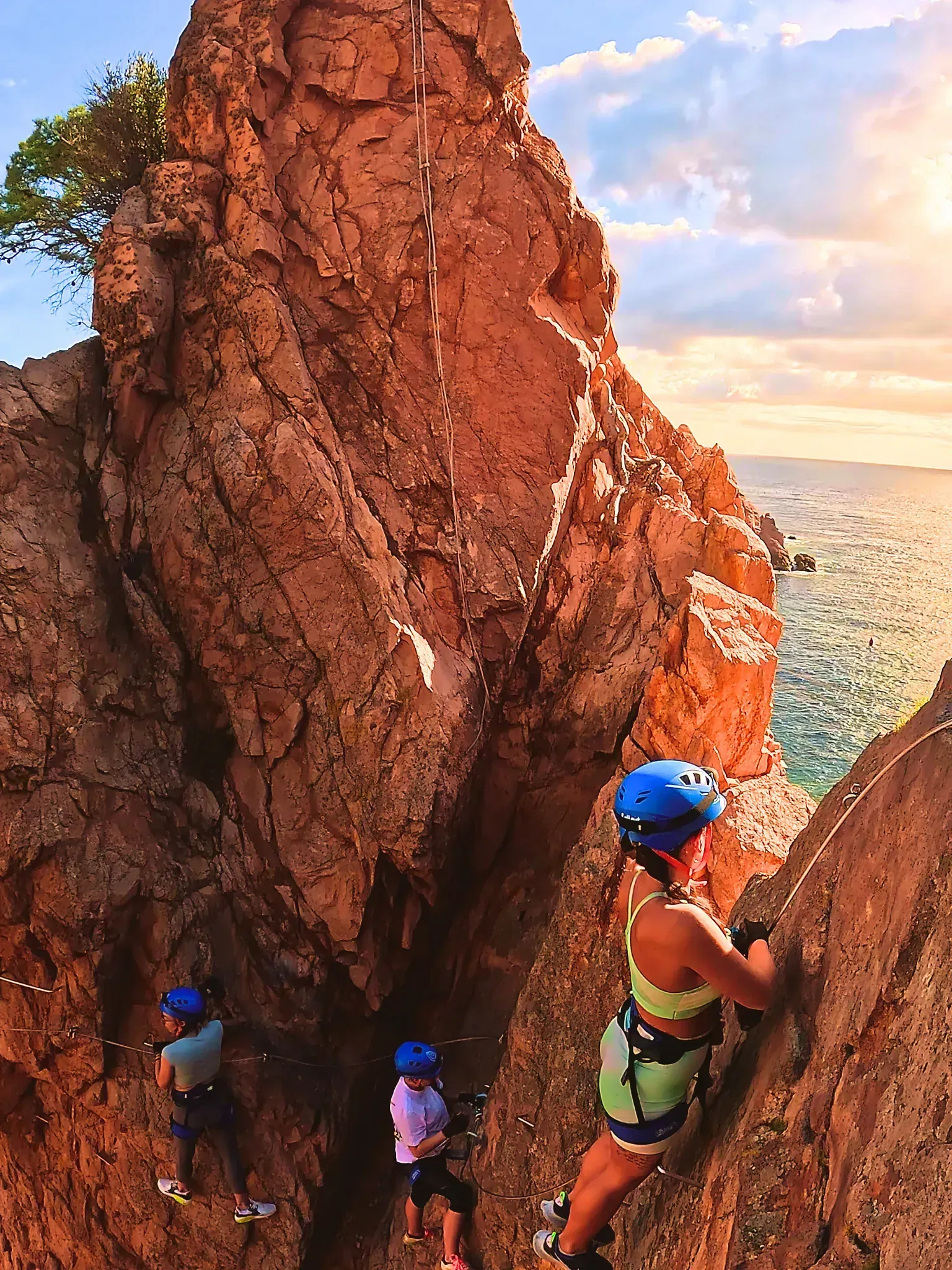Un grupo de personas está escalando un acantilado rocoso con vistas al océano.