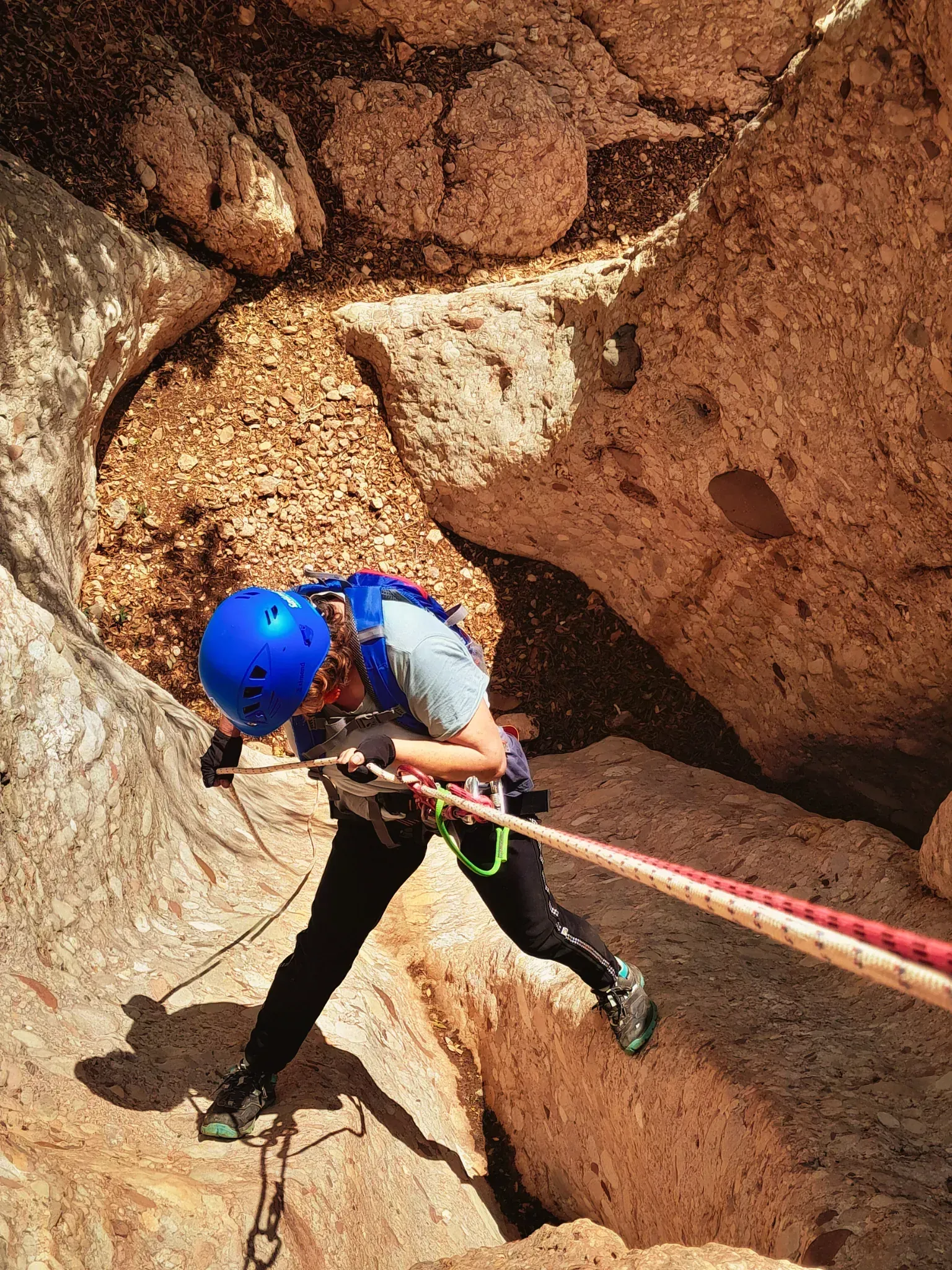 Una persona con un casco azul está escalando una pared de roca con una cuerda.