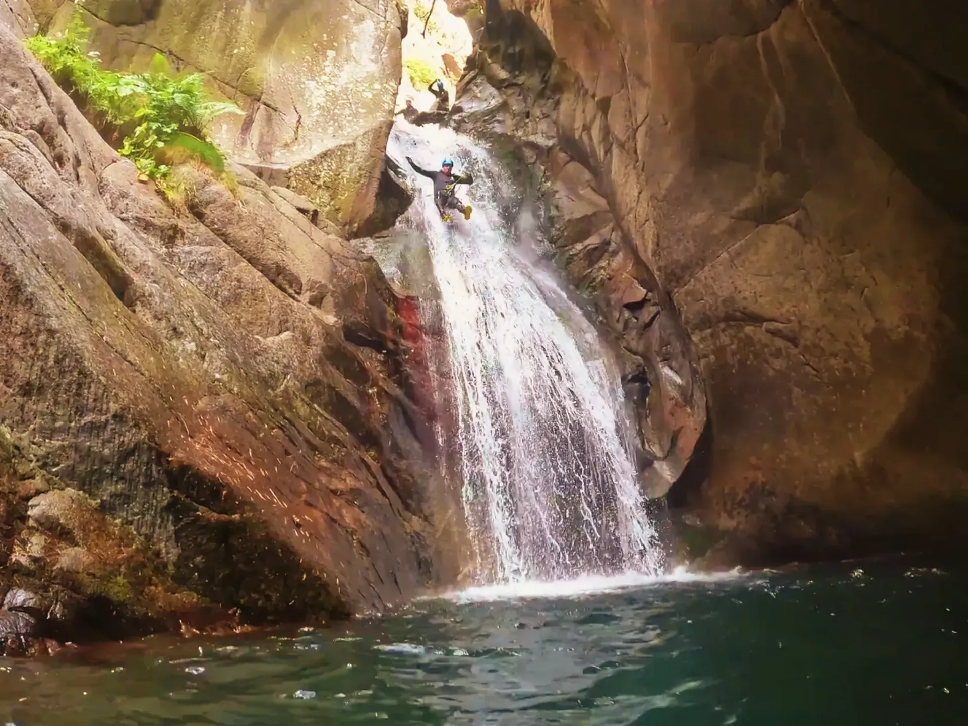 Una cascada baja por un acantilado hacia un cuerpo de agua.