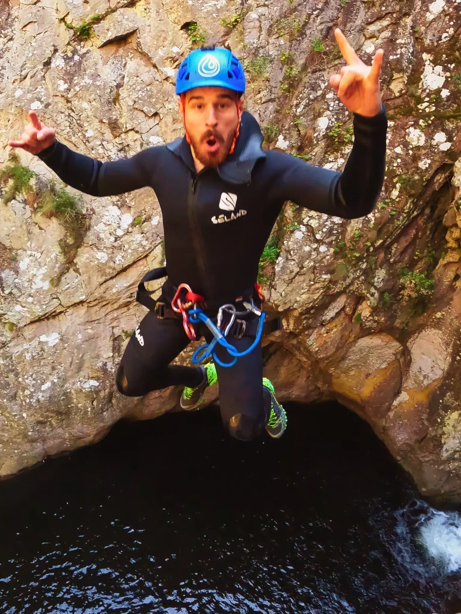 Un hombre que lleva un casco azul está saltando a un cuerpo de agua.