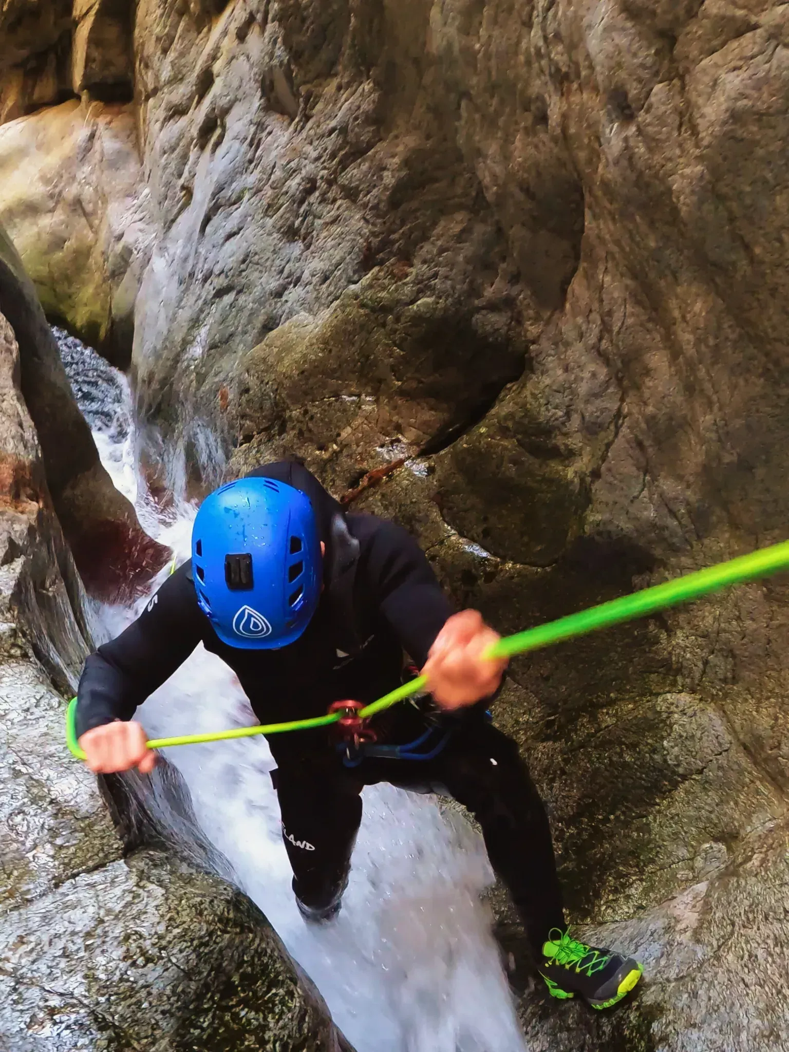 Un hombre con un casco azul está escalando una cascada con una cuerda.