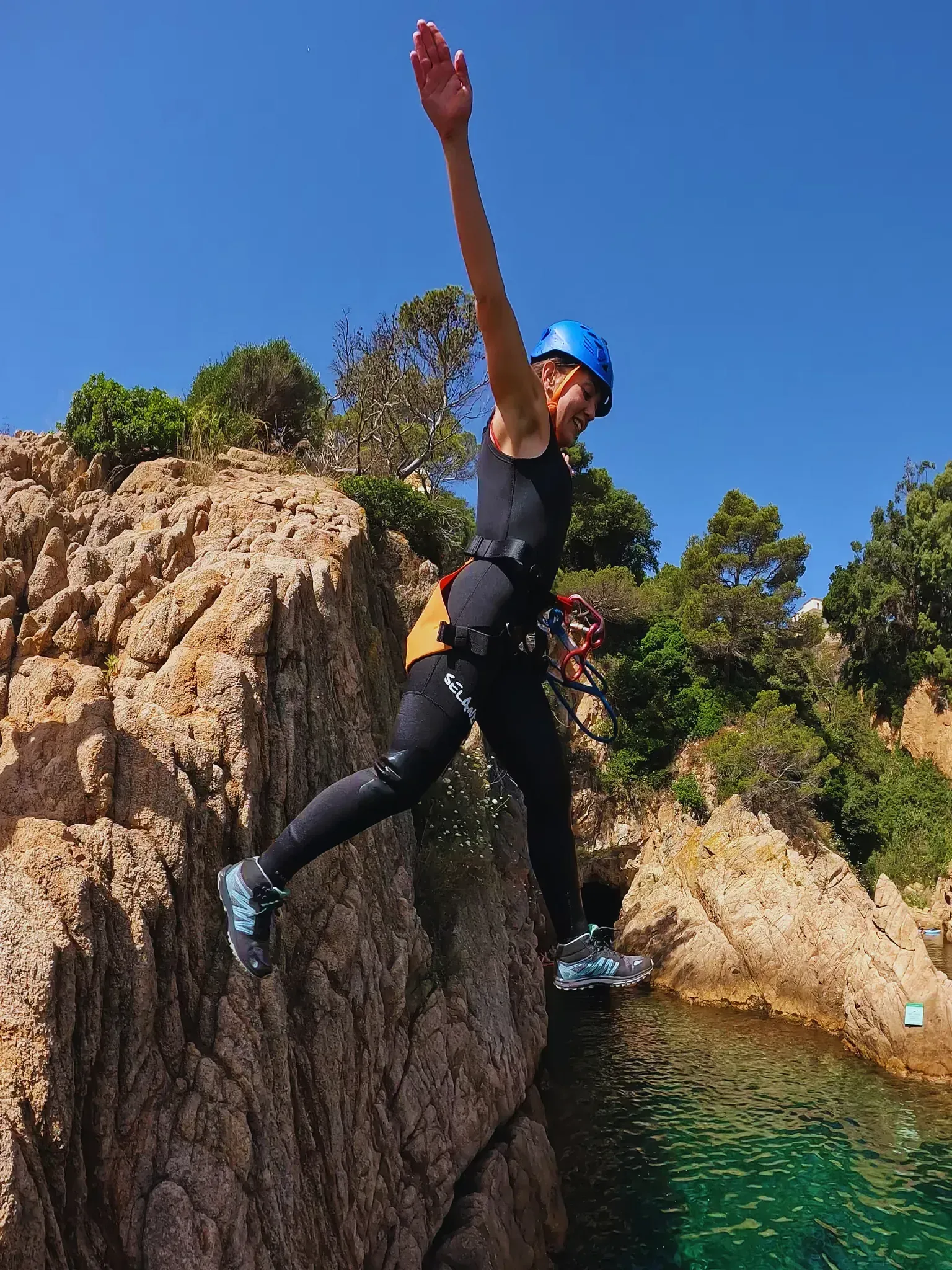 Una persona está saltando desde una roca al agua.