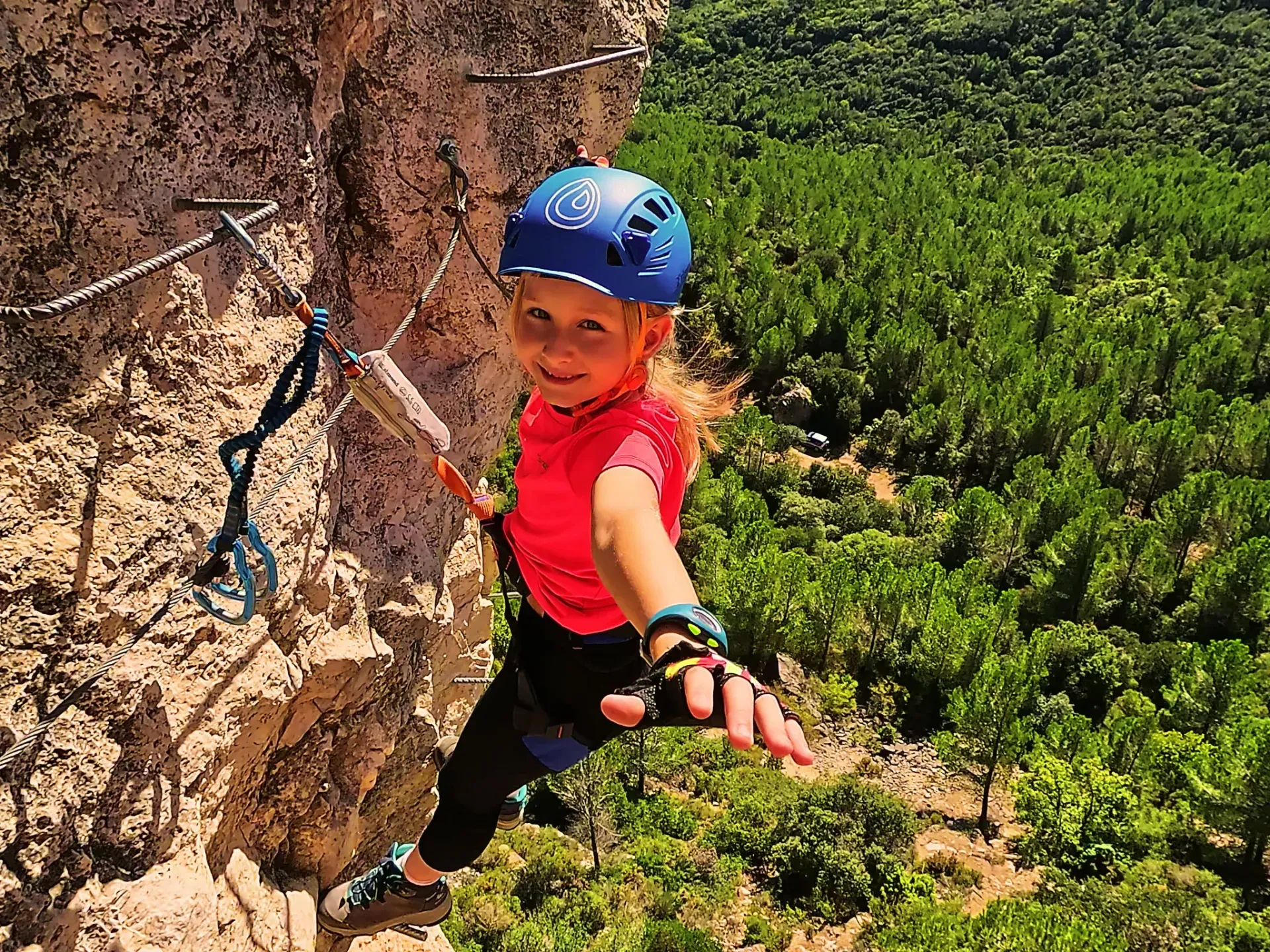 Una niña que lleva un casco está escalando una pared de roca.