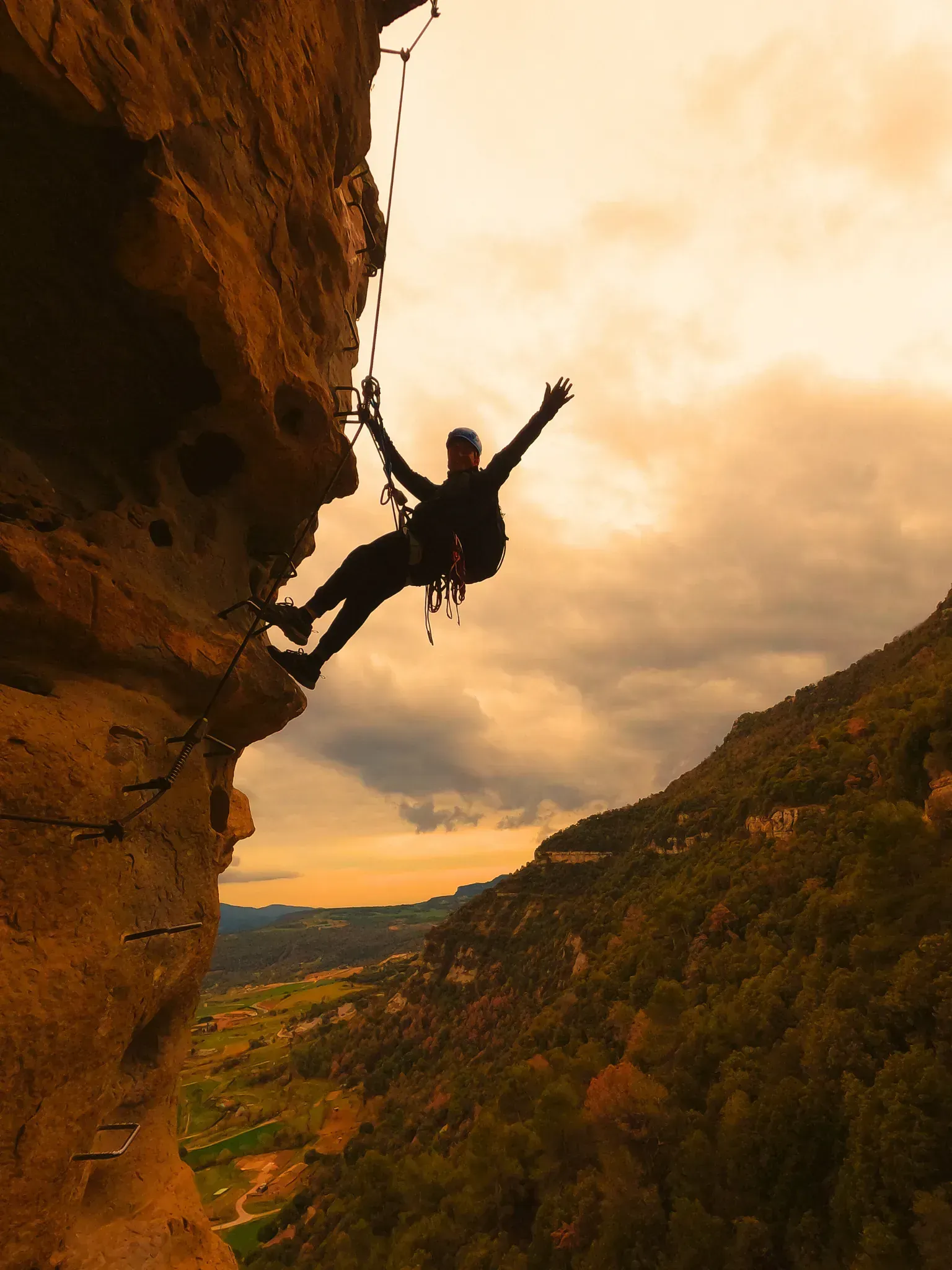 Una persona está subiendo un acantilado con los brazos extendidos.