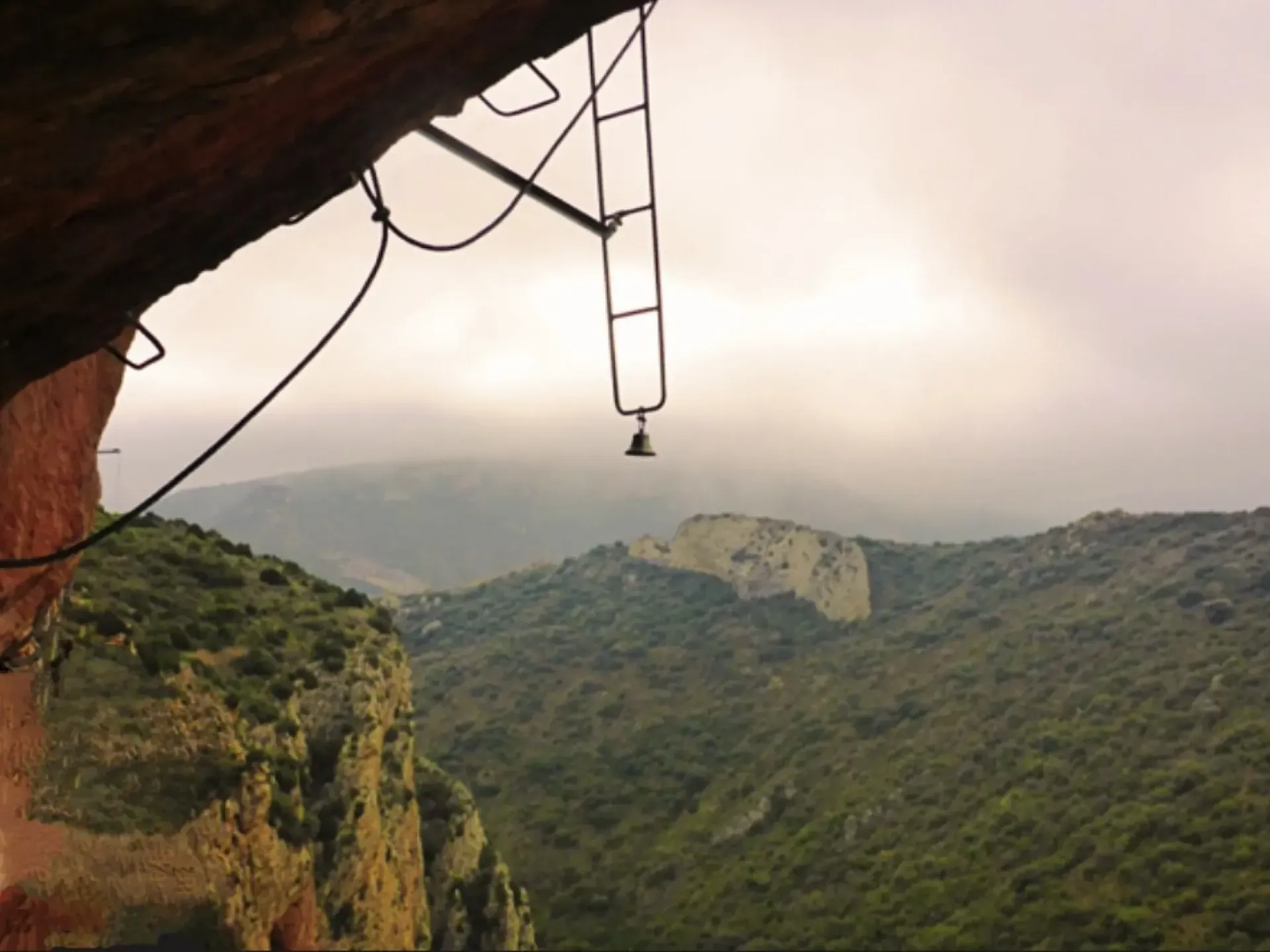 Una campana cuelga de una cuerda en las montañas.