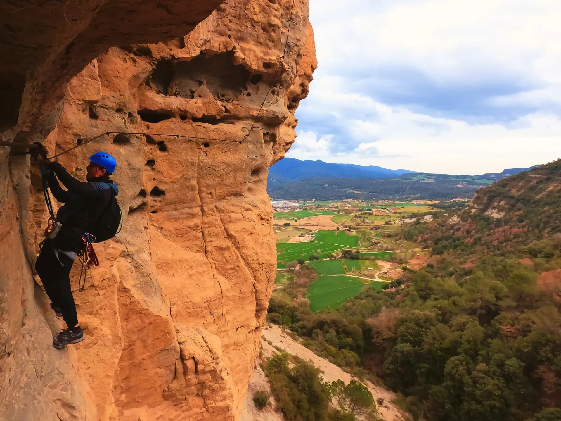 Un hombre con un casco azul está escalando una pared de roca.