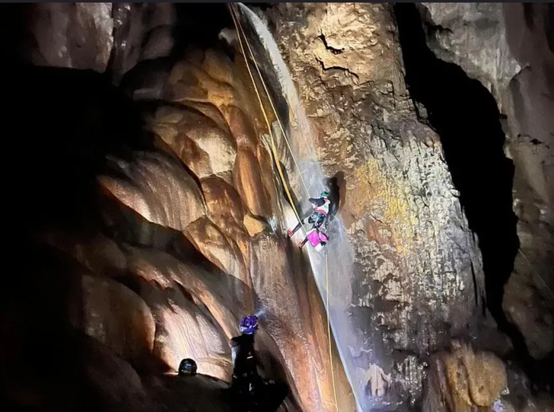 Un grupo de personas está escalando una cascada en una cueva.