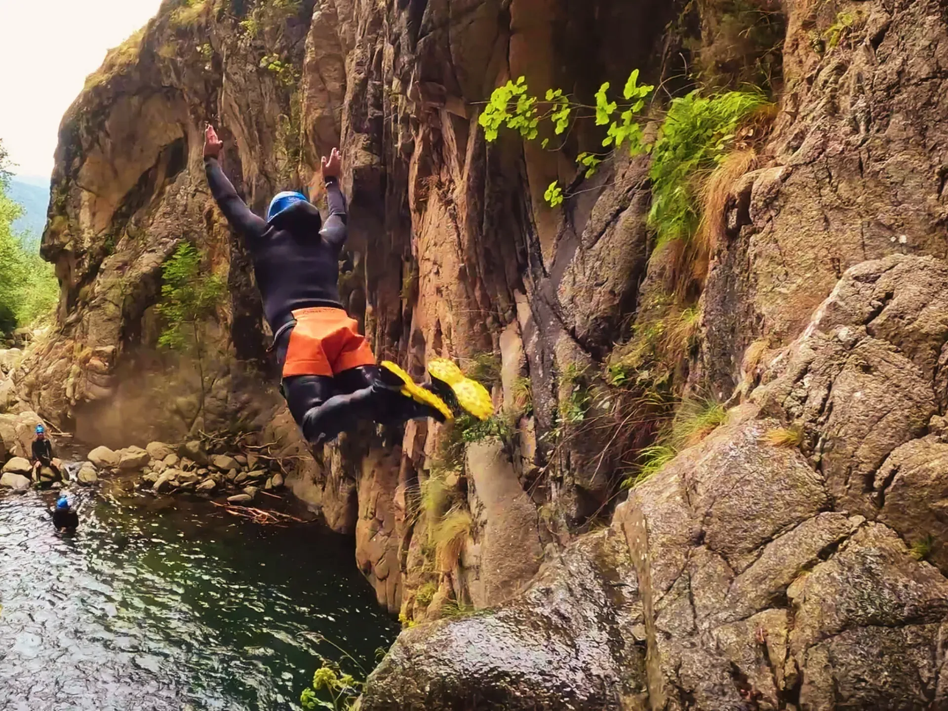 Un hombre está saltando desde un acantilado a un cuerpo de agua.
