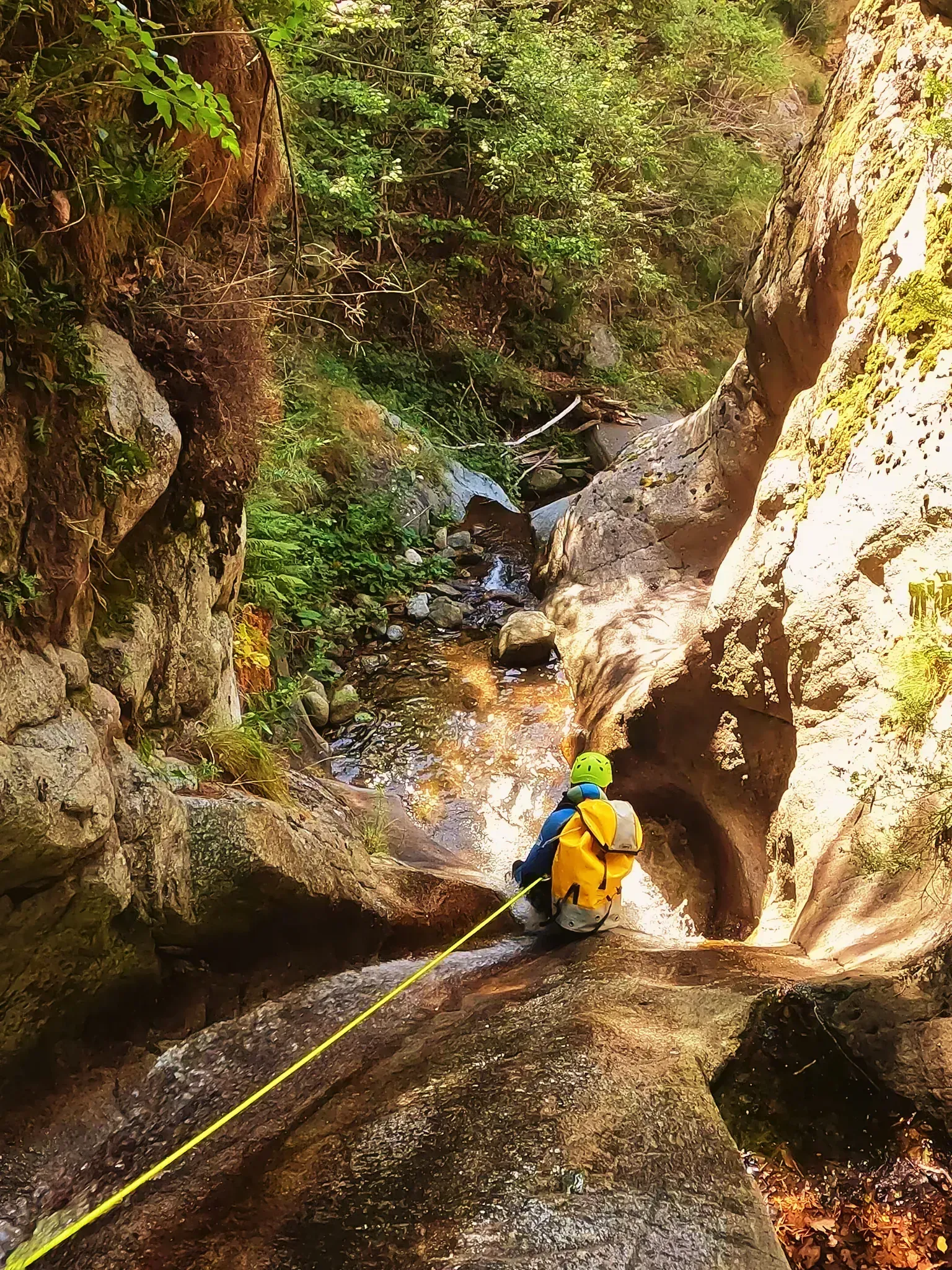 Una persona está bajando por una cascada con una cuerda.