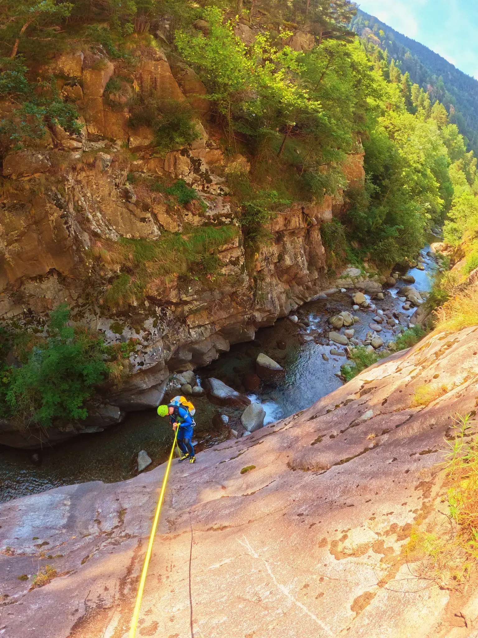 Una persona está subiendo un acantilado al lado de un río.