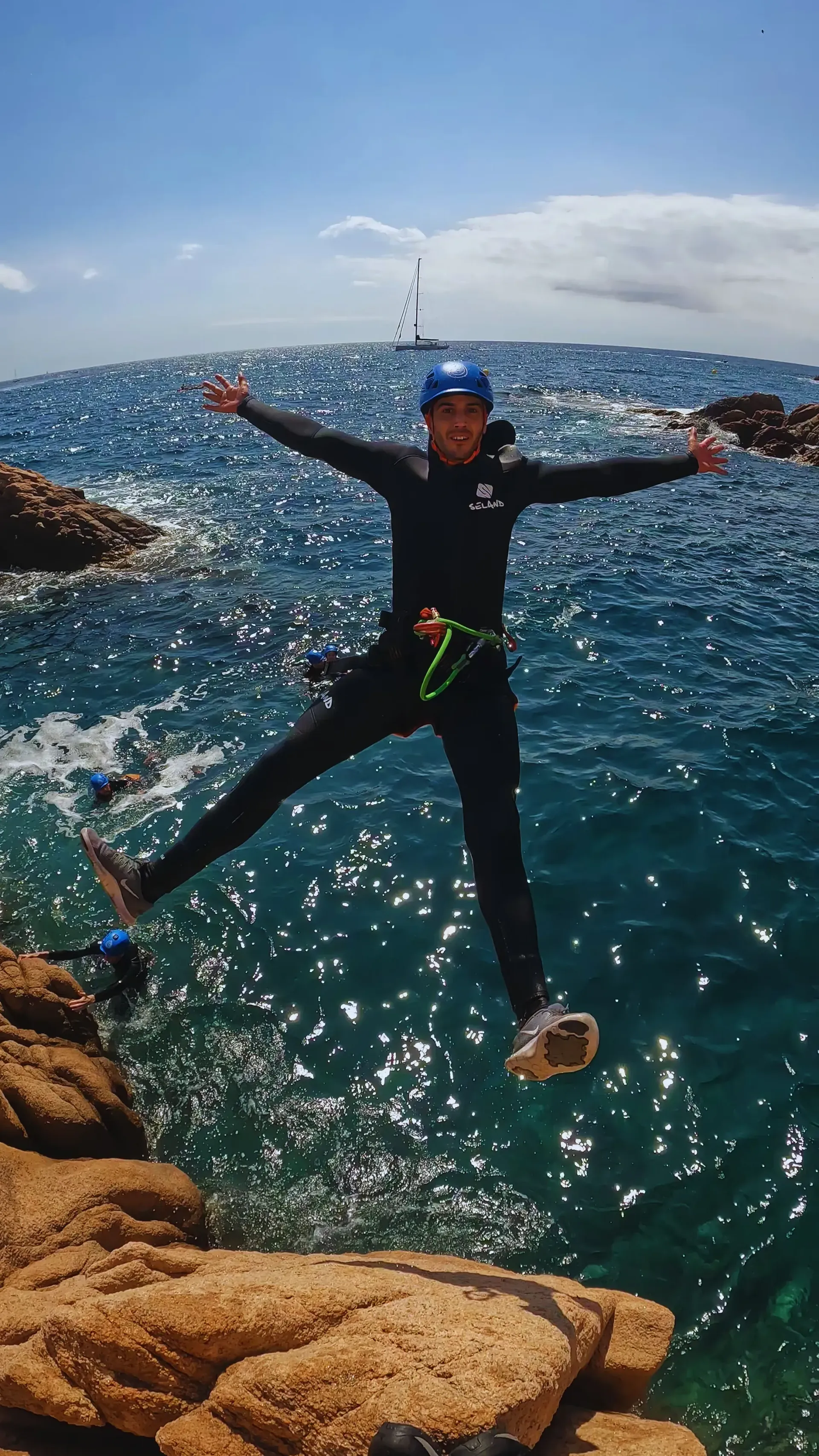 Una persona está saltando al océano desde un acantilado rocoso.