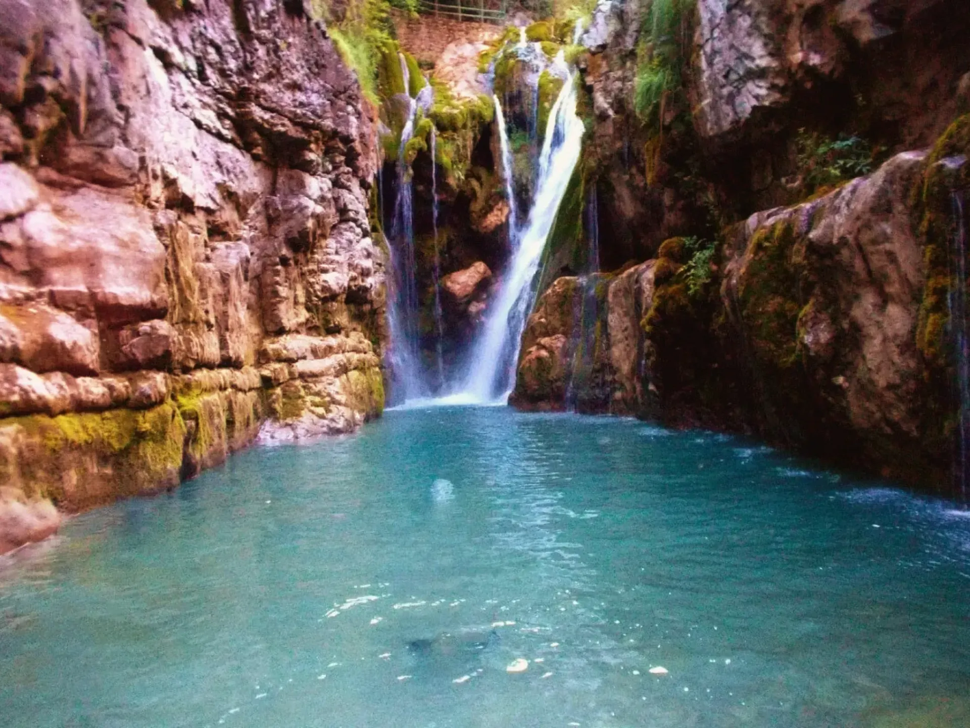 Una cascada está rodeada de rocas y un charco de agua.