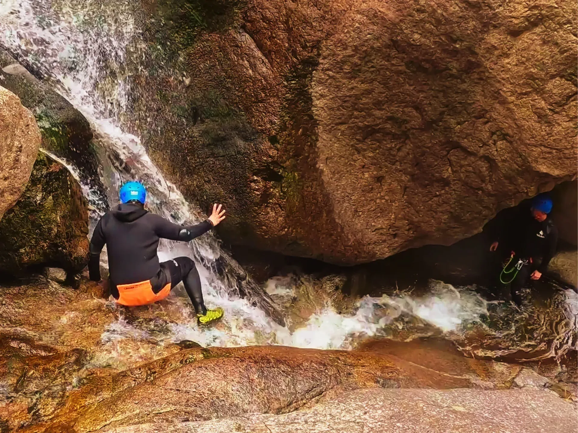 Un hombre está sentado en una roca al lado de una cascada.
