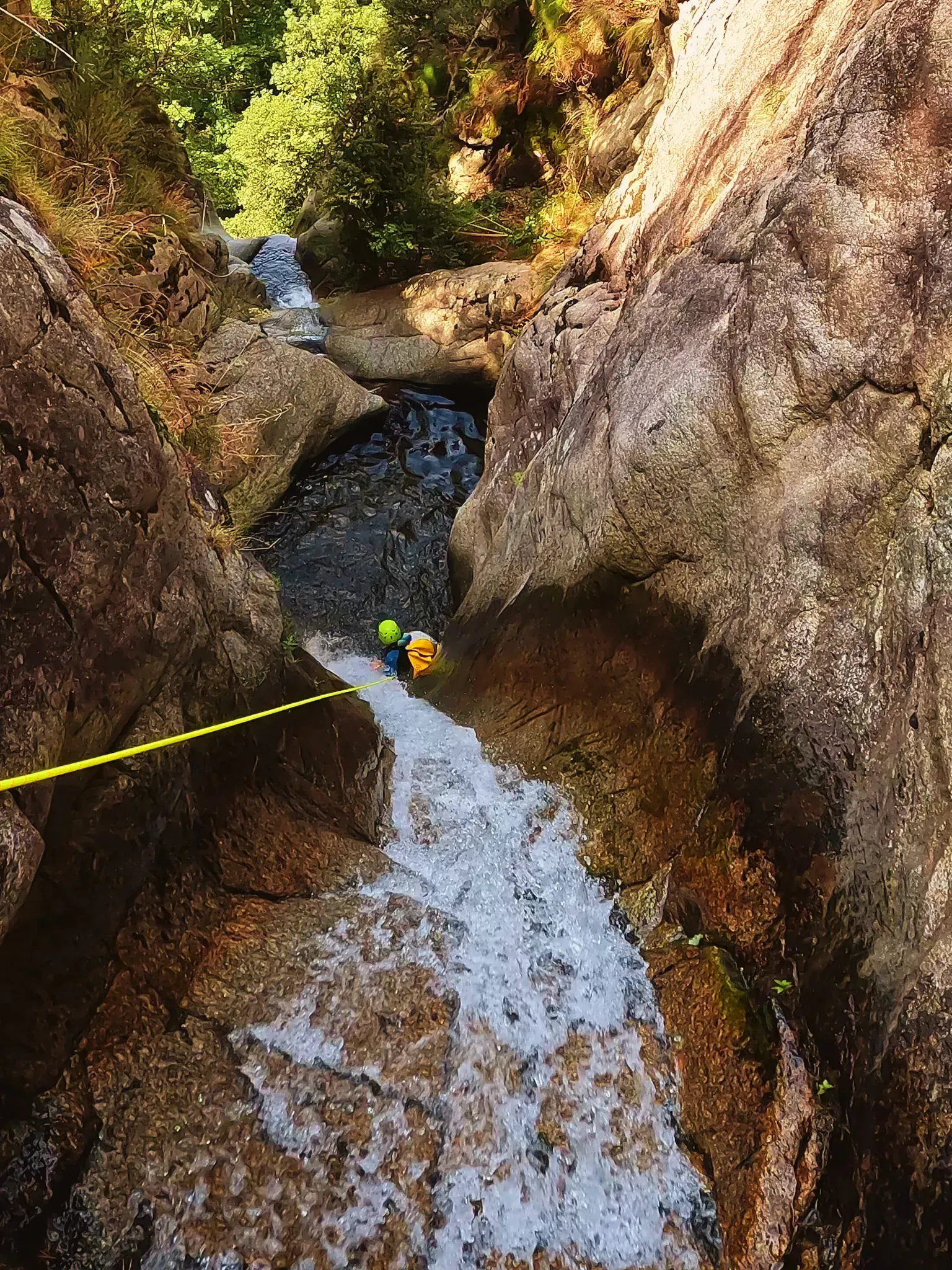 Una persona baja por una cascada con una cuerda.