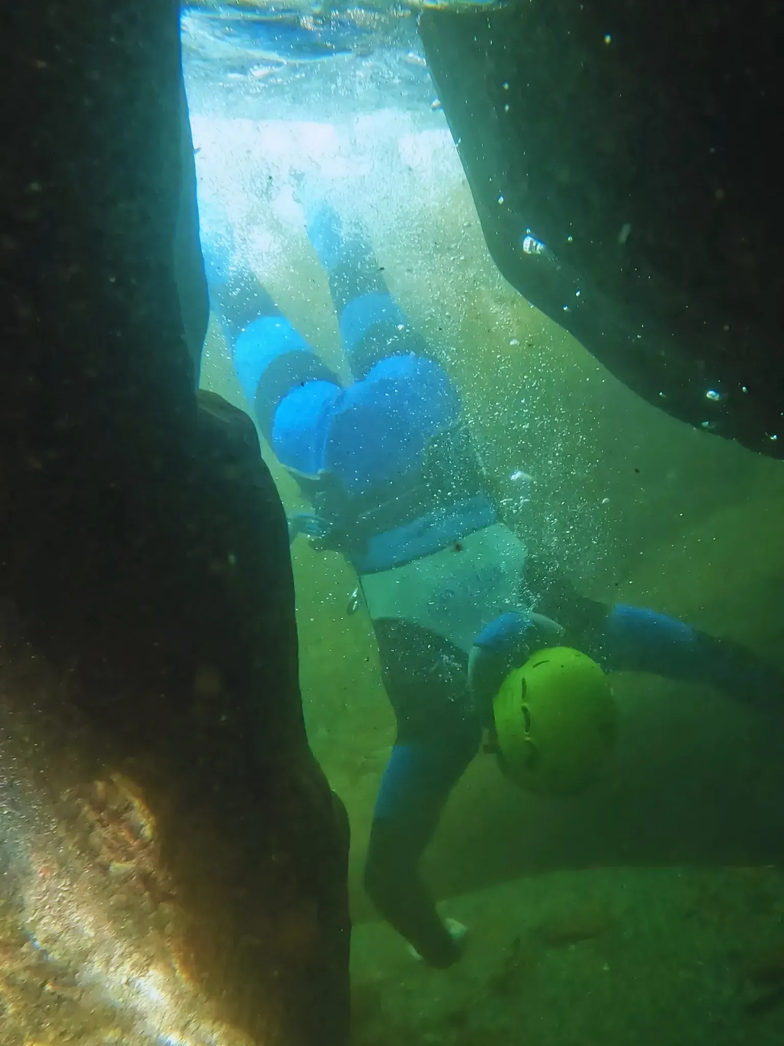 Una persona está nadando bajo el agua con un casco amarillo.