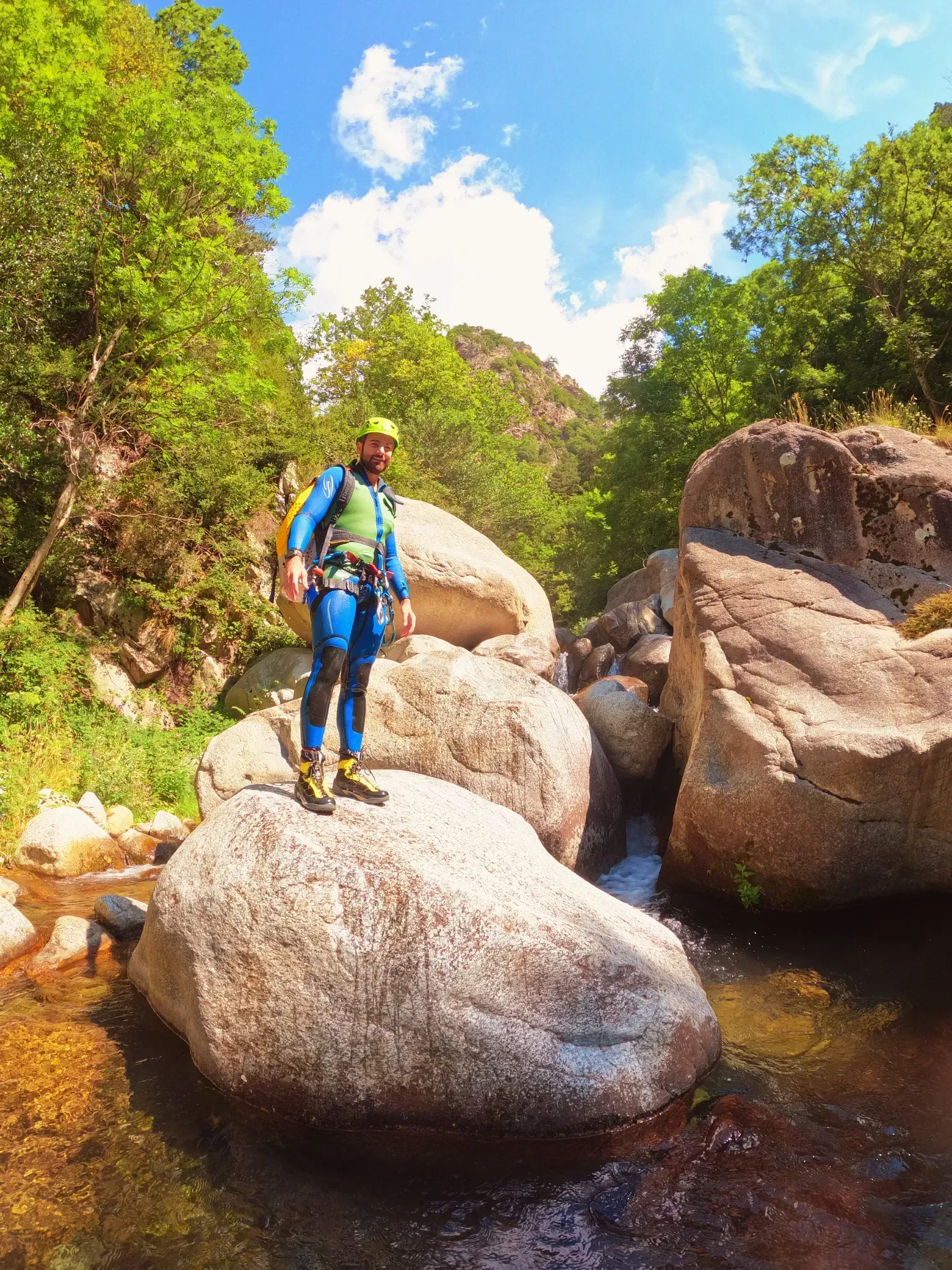 Un hombre está de pie sobre una roca con vistas a un río.