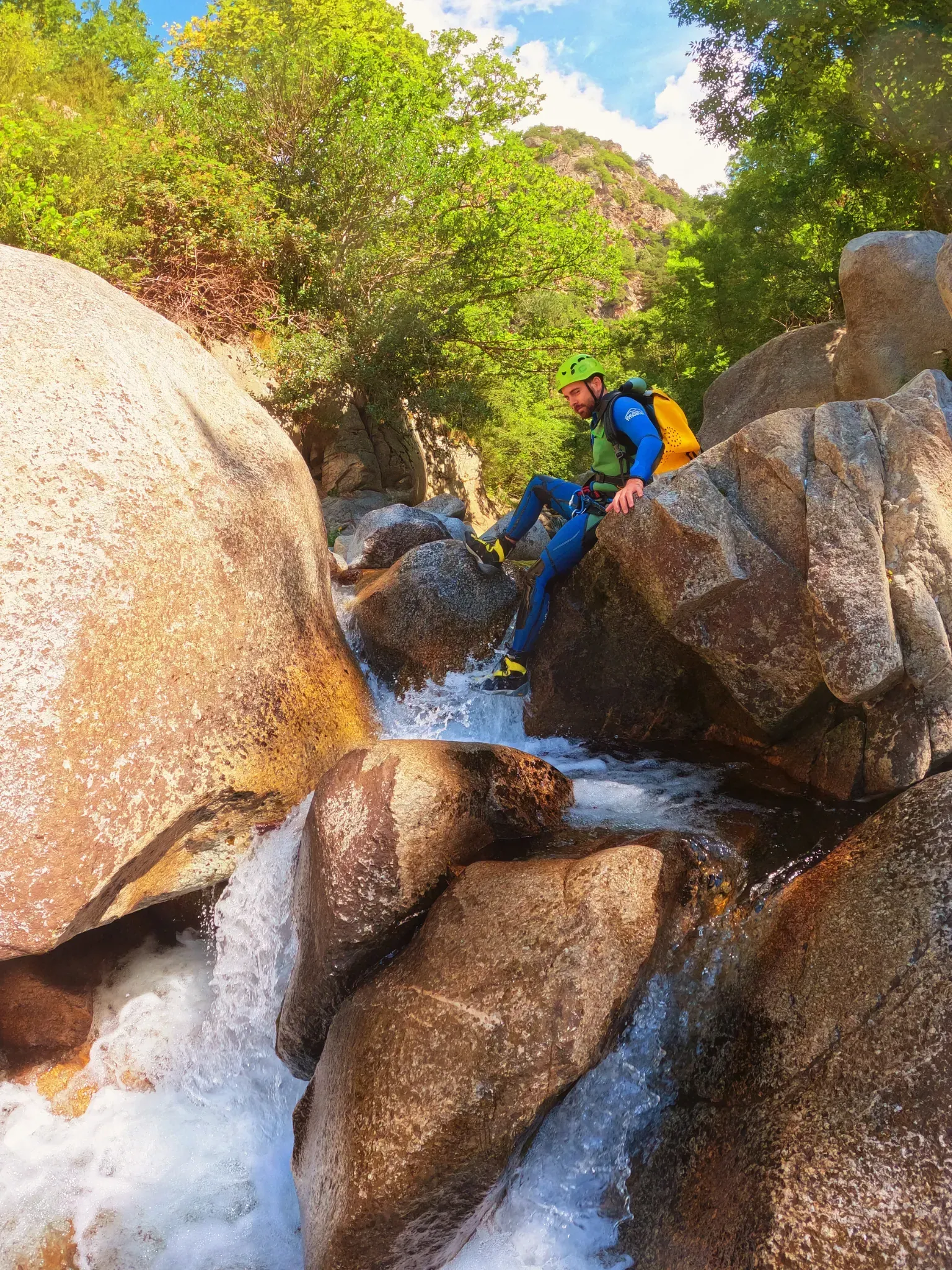Un hombre está sentado en una roca al lado de una cascada.