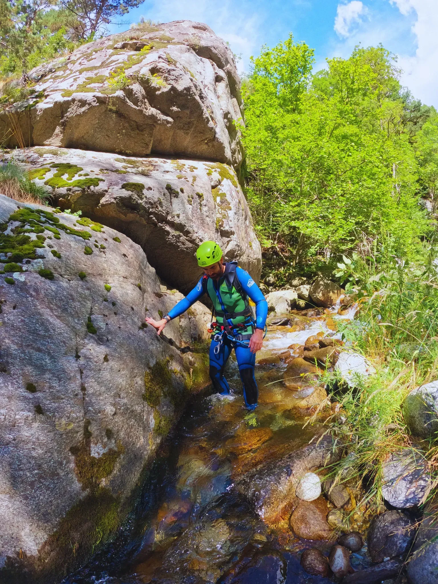 Un hombre camina a través de un río entre dos rocas.