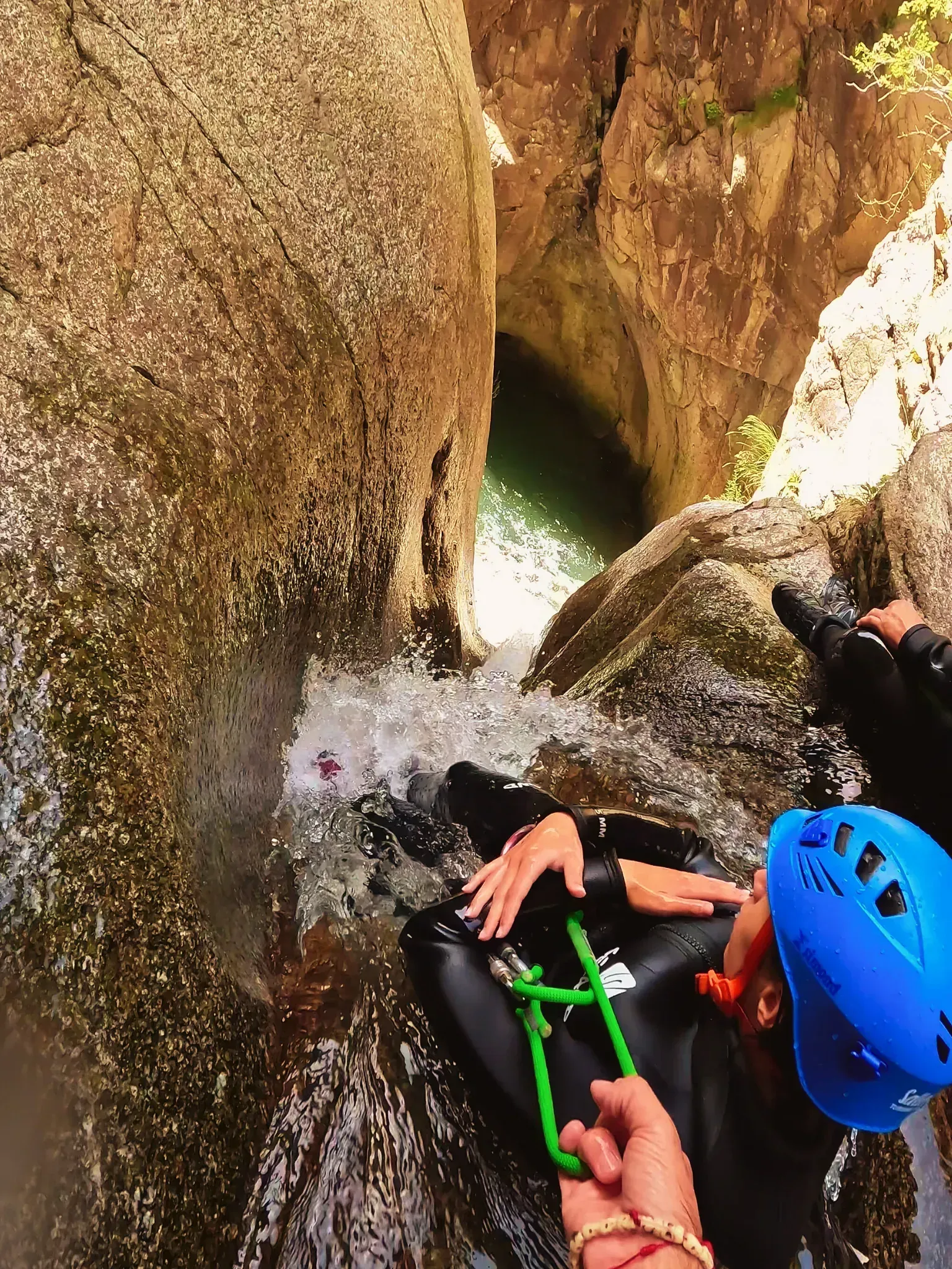 Una persona que lleva un casco azul está sentada en una cascada.