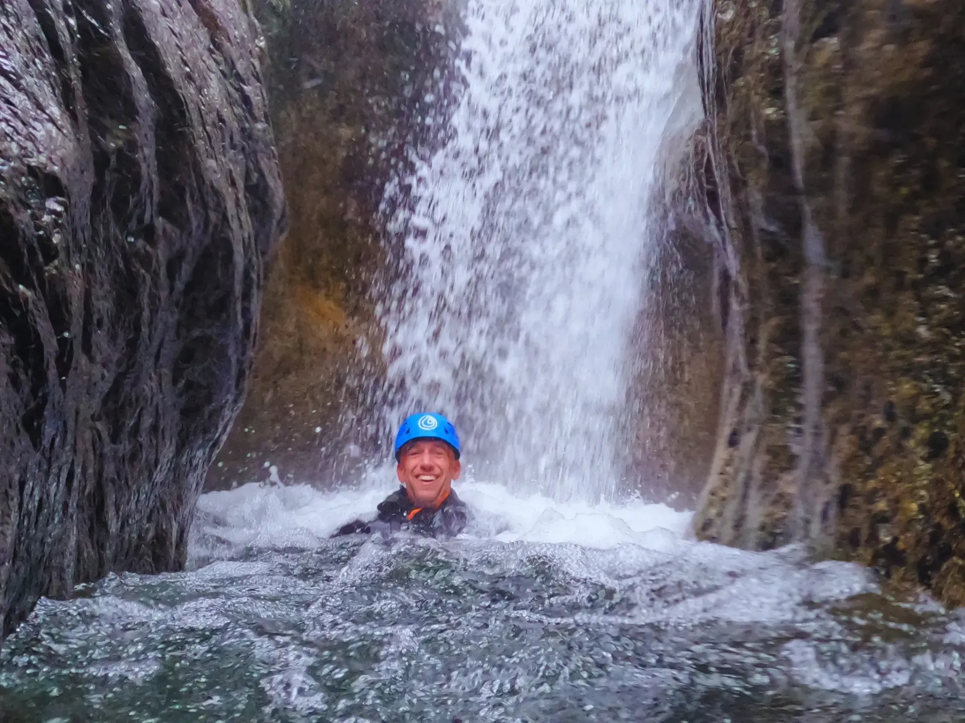 Un hombre con un casco azul está nadando en una cascada.