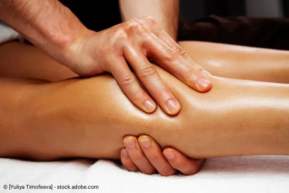 Eine Person massiert mit ihren Händen das Bein einer anderen Person.