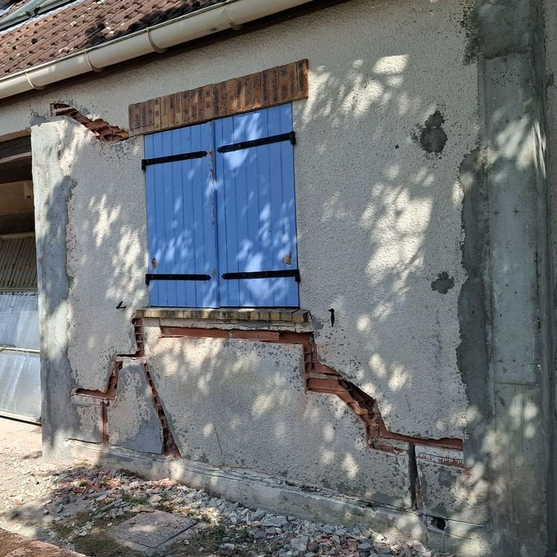 Mur extérieur aux volets bleus en cours de rénovation.