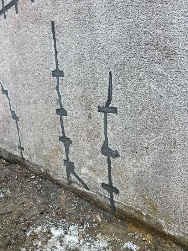 Mur extérieur avec plusieurs fissures réparées.