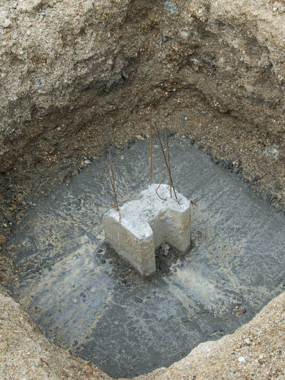 Poteau de fondations en béton dans un trou carré creusé.