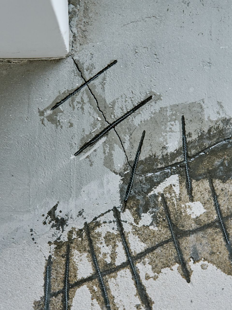 Plancher en béton endommagé avec barres d'armature exposées et eau.