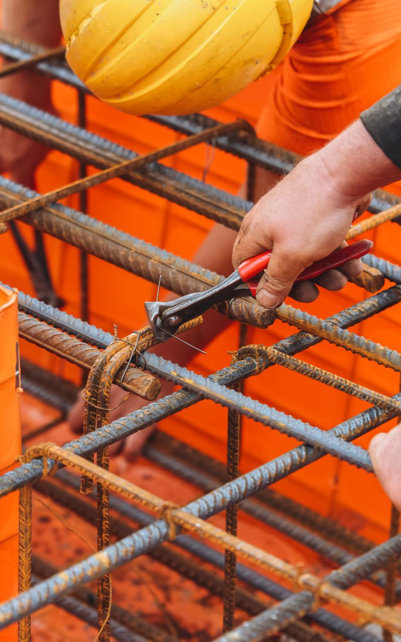 Un ouvrier du bâtiment utilise des pinces pour fixer des barres d'armature.