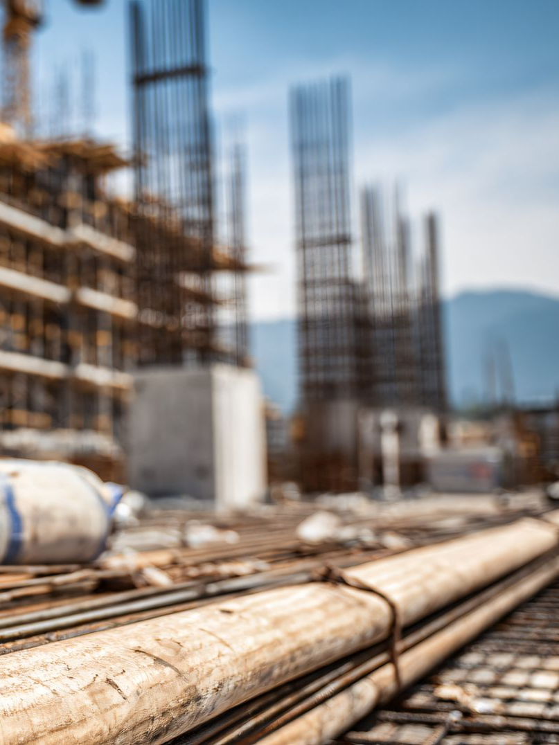 Chantier de construction avec barres d'armature et charpente en acier contre un ciel flou.