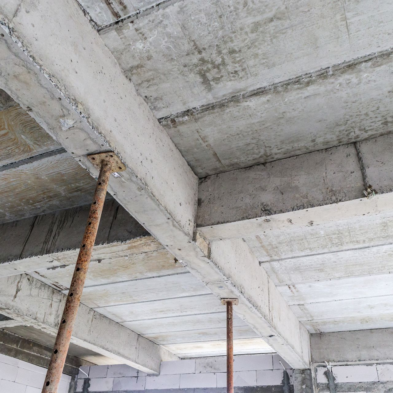Plafond en béton en construction, soutenu par des poutres métalliques.