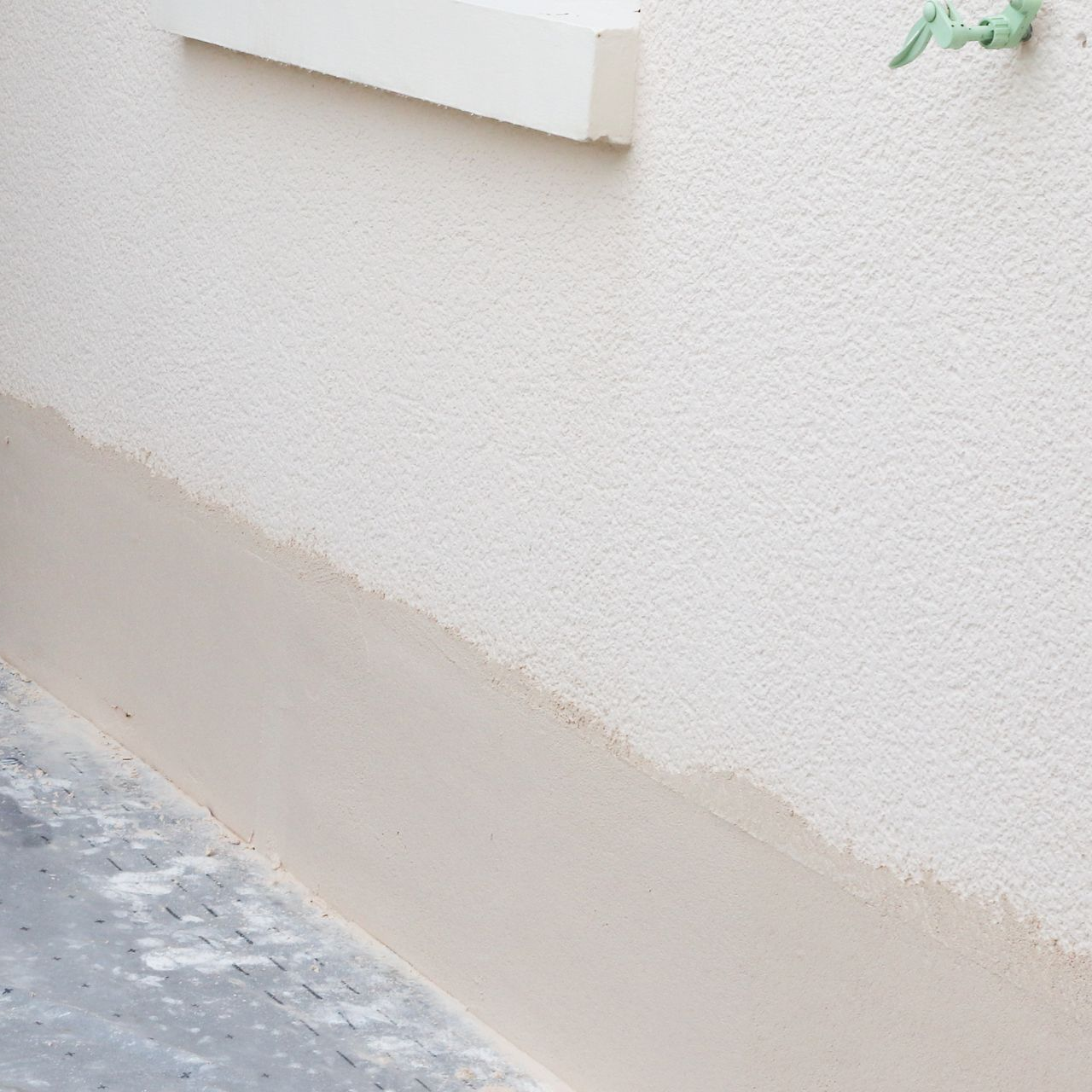 Mur texturé blanc avec une bande plus claire en bas.