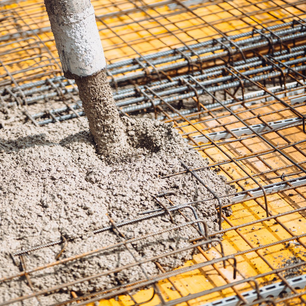 Du béton est coulé à partir d'un tuyau sur une grille de barres d'armature sur une surface en bois.