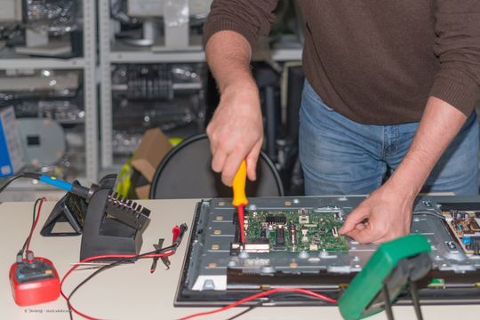 Oberkörper eines Menschen mit Elektronik auf dem Tisch