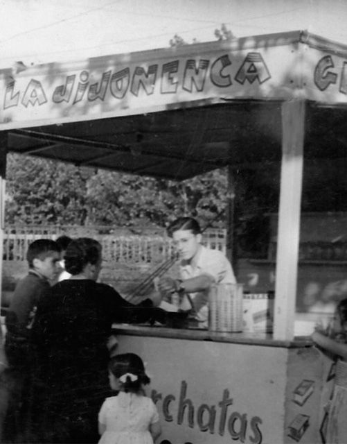 Una foto en blanco y negro de personas paradas debajo de un cartel que dice la jabonenca