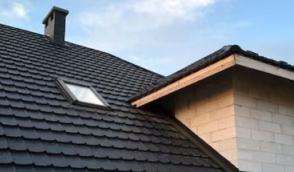 Le toit d'une maison avec une lucarne et une cheminée.