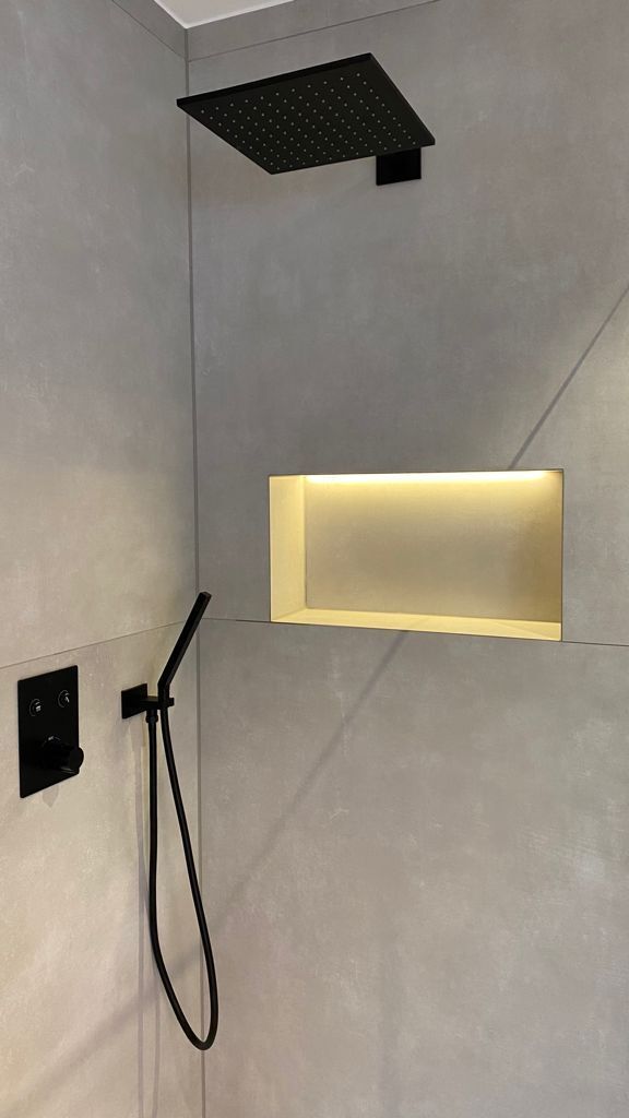 Renovierte Dusche mit Betonoptik Fliesen und schwarzen Armaturen