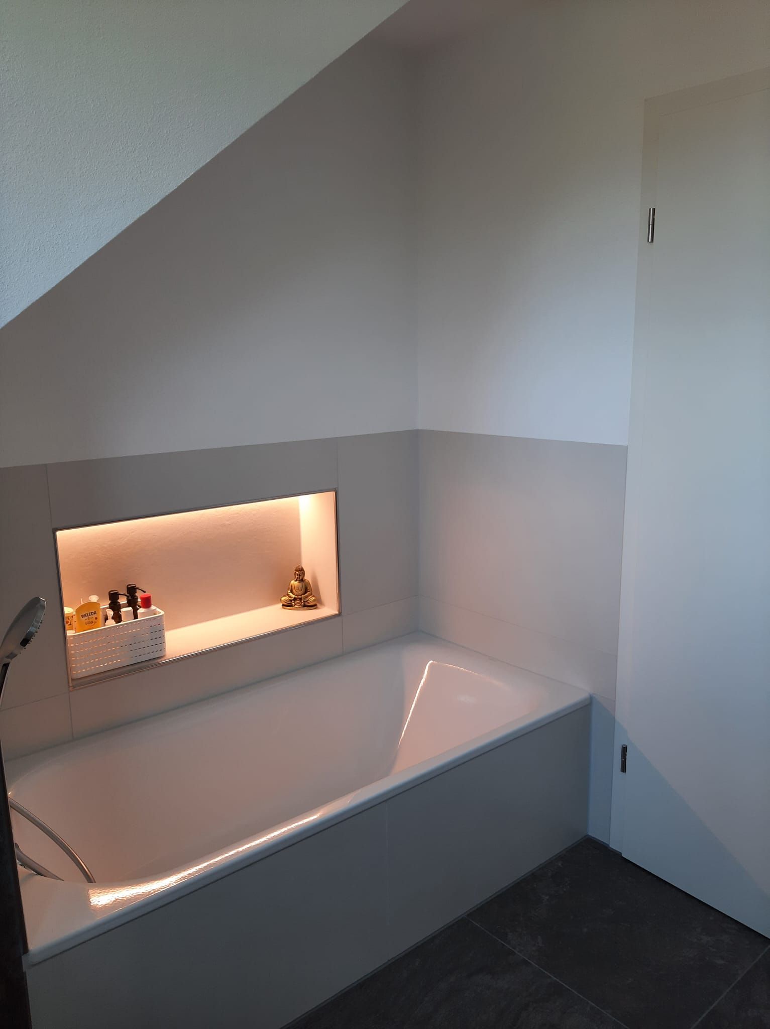 ein Badezimmer mit einer Badewanne und einem Regal in der Wand .