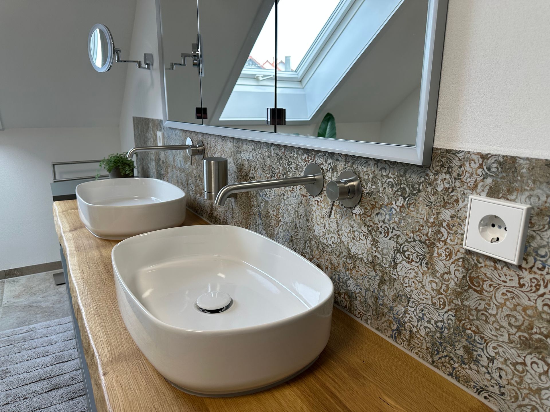 Moderner Badezimmer-Waschtisch mit zwei weißen Aufsatzwaschbecken, Wandspiegel und Oberlicht über einer Holzarbeitsplatte.