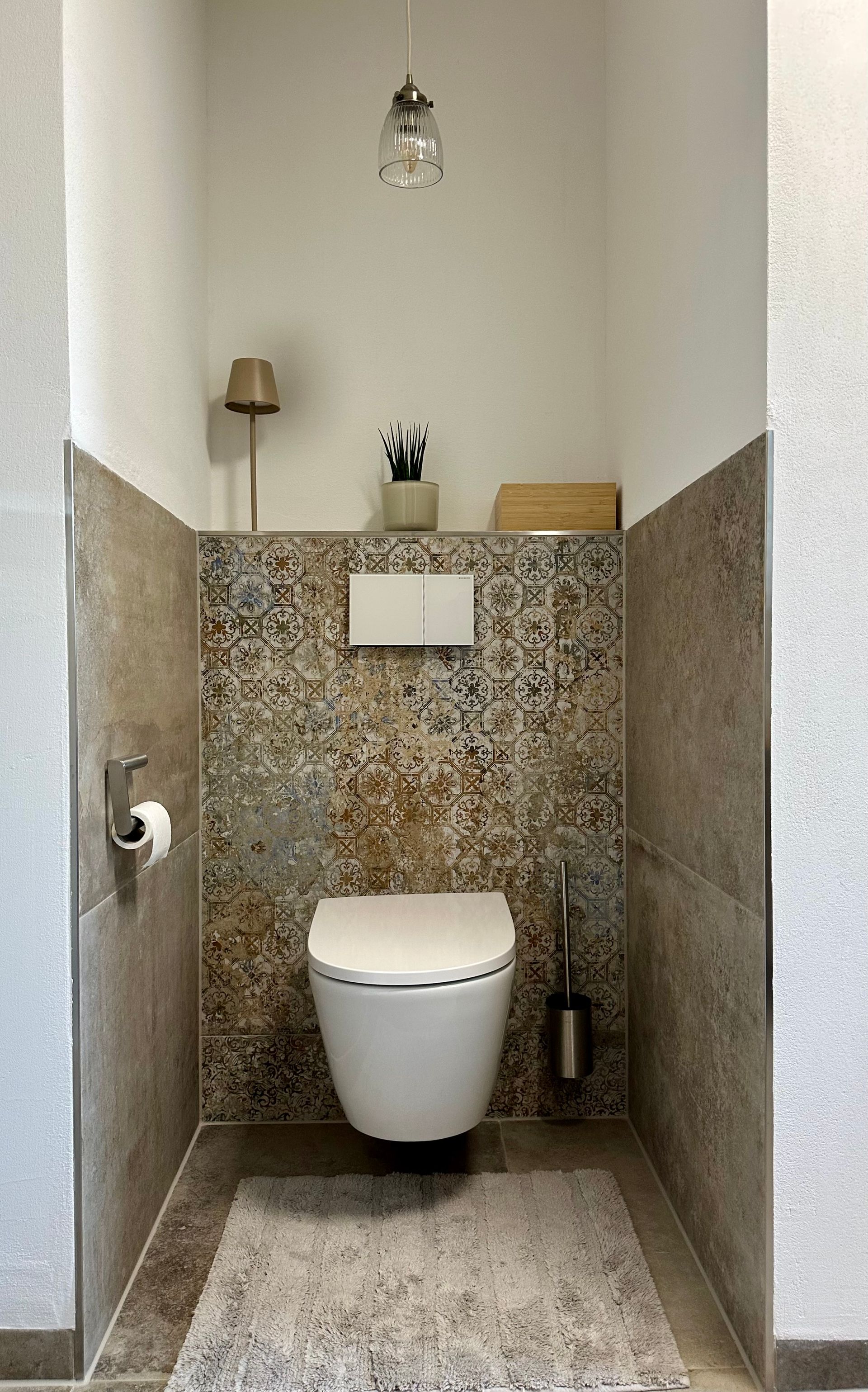 Moderne, minimalistische Toilettennische mit wandhängendem WC, gesprenkelten Fliesen und beigefarbenen Akzenten