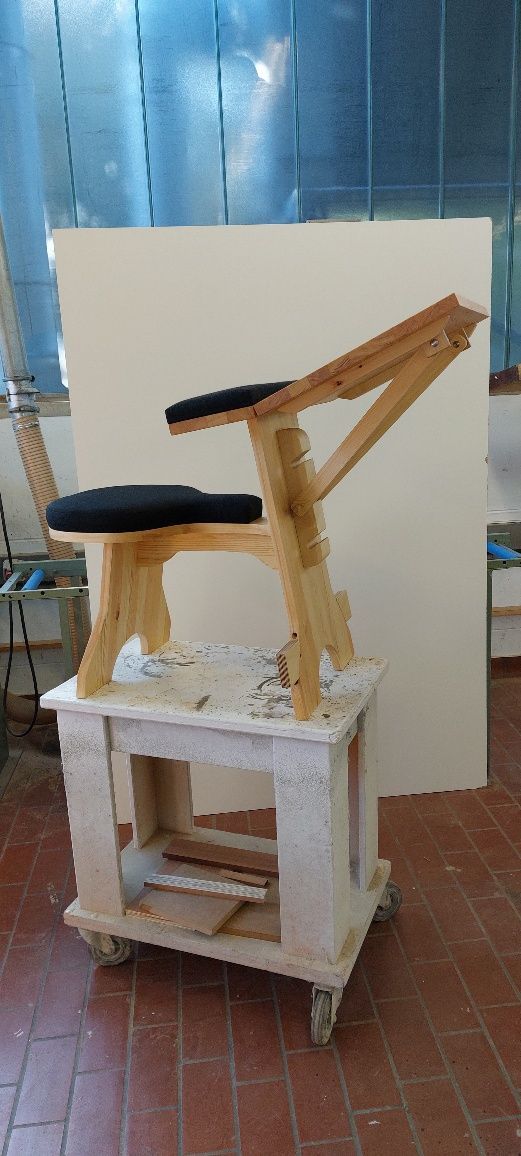 In einem Raum steht ein Holzstuhl auf einem weißen Tisch.