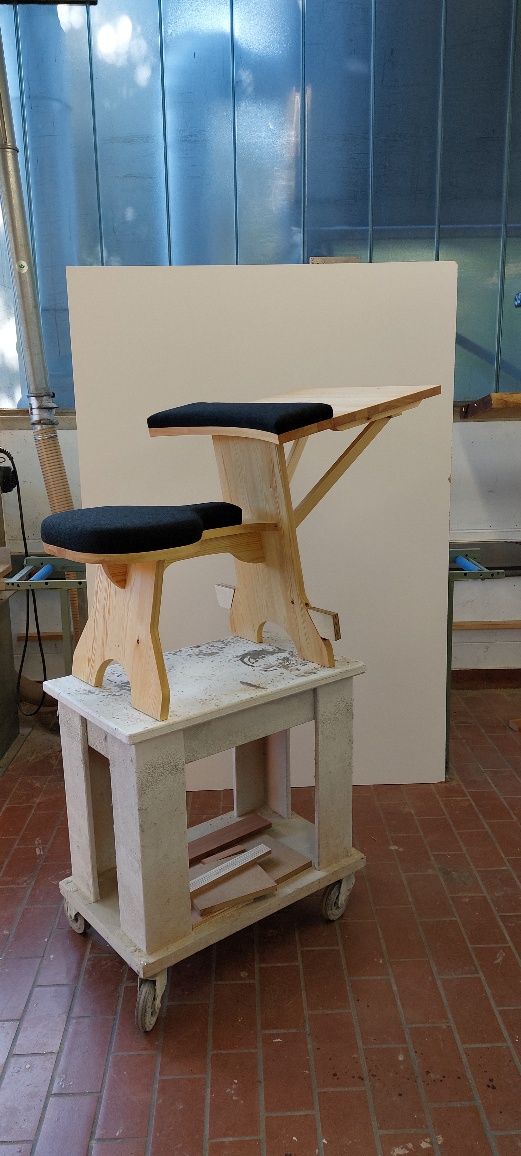 In einem Raum steht ein Holzhocker auf einem Holztisch.