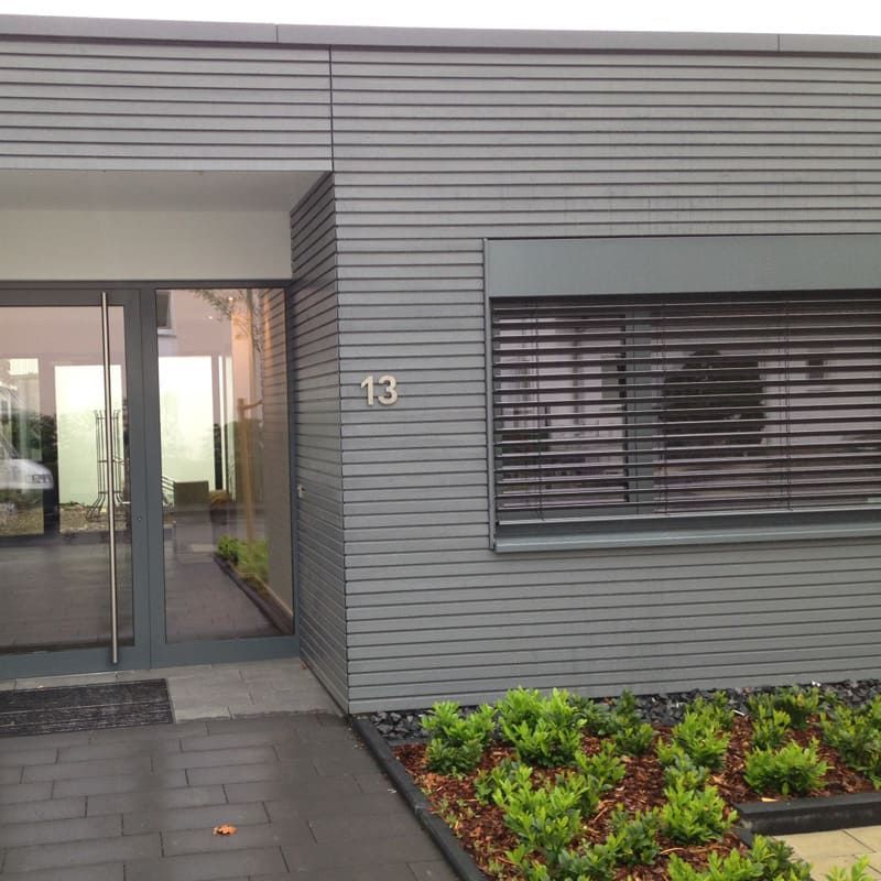 Ein graues Haus mit der Nummer 13 auf der Vorderseite