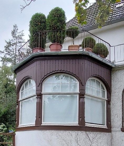 Ein Haus mit einem Balkon und Topfpflanzen darauf.