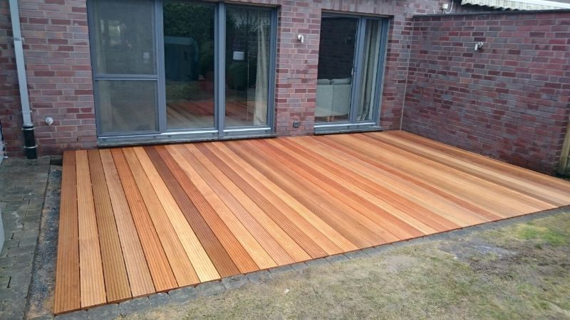Vor einem Backsteingebäude befindet sich ein Holzdeck.
