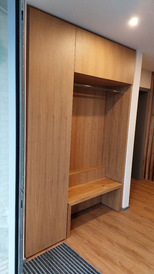Ein Flur mit Holzschränken und einer Bank.