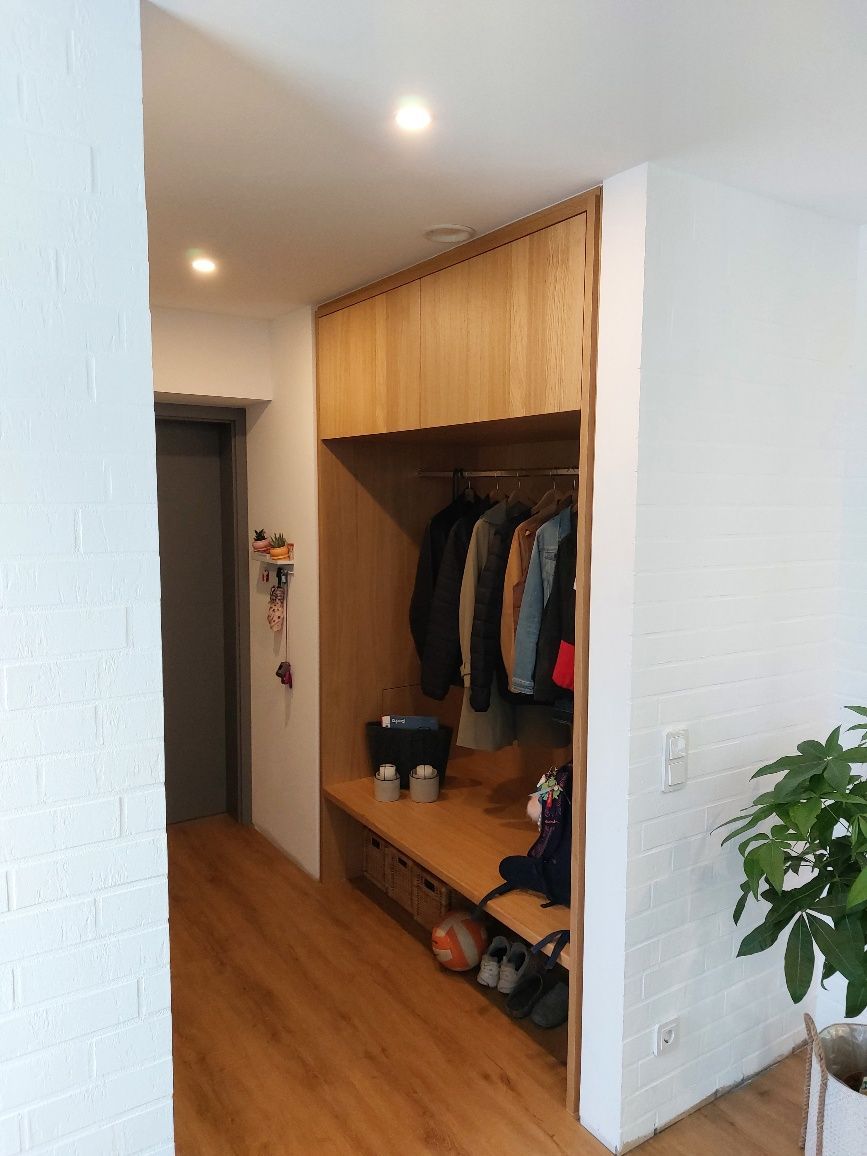 Ein Flur mit Holzboden und einem Schrank voller Kleidung und Schuhe.